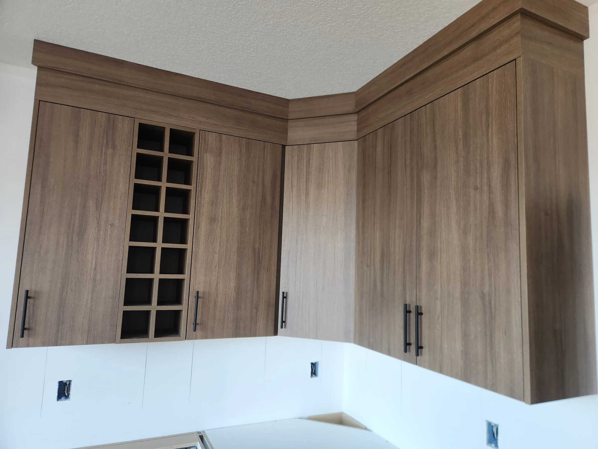 Woodgrain uppers with a built-in wine rack, an angled corner cabinet and continuous crown to the ceiling